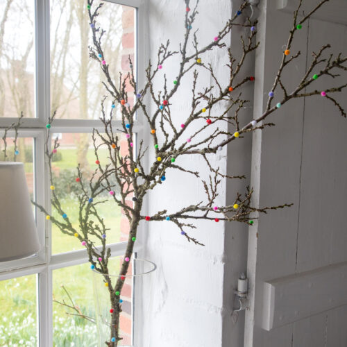 Frühlingshafte Dekoidee: Ein bunter Pompom-Ast! Einfach selbst gemacht, bringt er Farbe & Frische in Euer Zuhause. Jetzt kreative Anleitung entdecken!