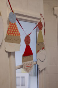 Zaubert eine niedliche Weihnachtsmann-Girlande aus bunten Papieren! Einfaches DIY f&uuml;r Kinder & Erwachsene, perfekt f&uuml;r Fenster, T&uuml;ren oder den Tannenbaum.