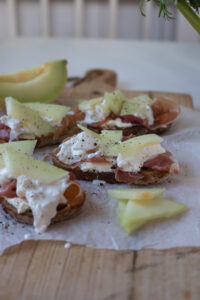 Knuspriges Grillbrot mit Frischk&auml;se, Schinken, orangener Melone und Burrata – ein schnelles, raffiniertes Rezept f&uuml;r Brunch oder Sommerabende.